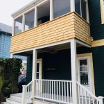 Two-story dark green house with a white porch and balcony, showcasing XTEND Contracting’s expertise in exterior remodeling and porch construction.