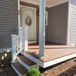 Front porch of a gray house with the number 336, featuring a decorative wreath and wooden steps, showcasing XTEND Contracting’s expertise in porch construction.