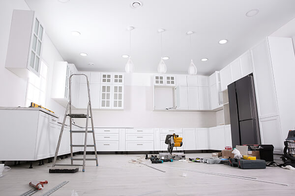 “A kitchen under renovation by XTEND Contracting, showcasing the installation of white cabinets and the use of various tools, symbolizing their expertise in home remodeling services.