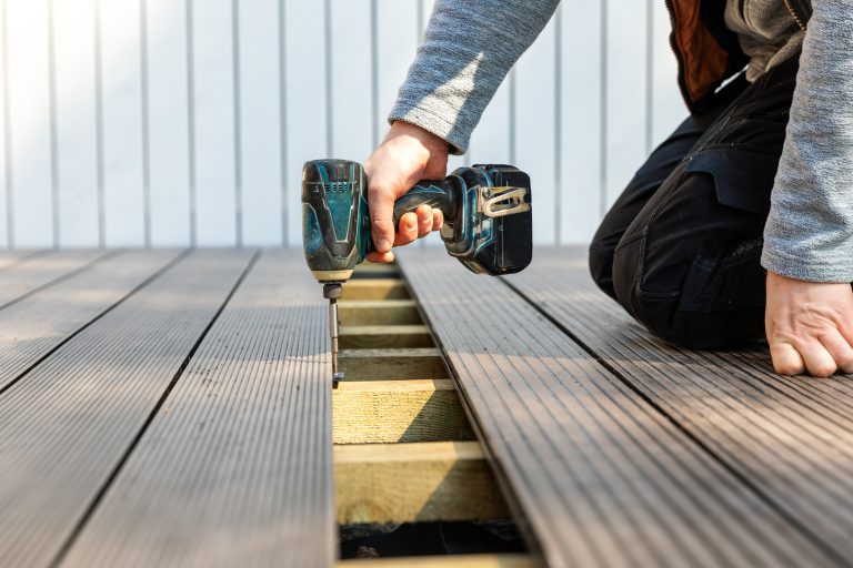 terrace deck construction - man installing wpc composite decking boards.
